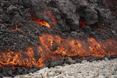 Вулканичната лава изгаря зелена растителност отстрани на пътя близо до